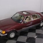 Front quarter view of a 1985 Mercedes-Benz 500 SEL in Cabernet Red, showcasing its classic W126 S-Class design.