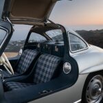 Front three quarter view of a silver 1955 Mercedes-Benz 300 SL Alloy Gullwing showcasing its iconic gullwing doors and sleek lines.