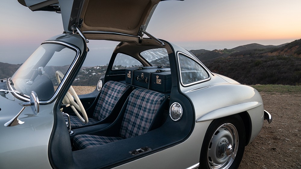 Front three quarter view of a silver 1955 Mercedes-Benz 300 SL Alloy Gullwing showcasing its iconic gullwing doors and sleek lines.