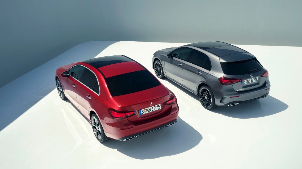 Exterior view of two Mercedes-Benz A-Class hatchbacks in a promotional setting, showcasing their modern and compact design.