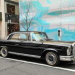 Black Mercedes Benz W111 Coupe front three quarter view, parked on street.