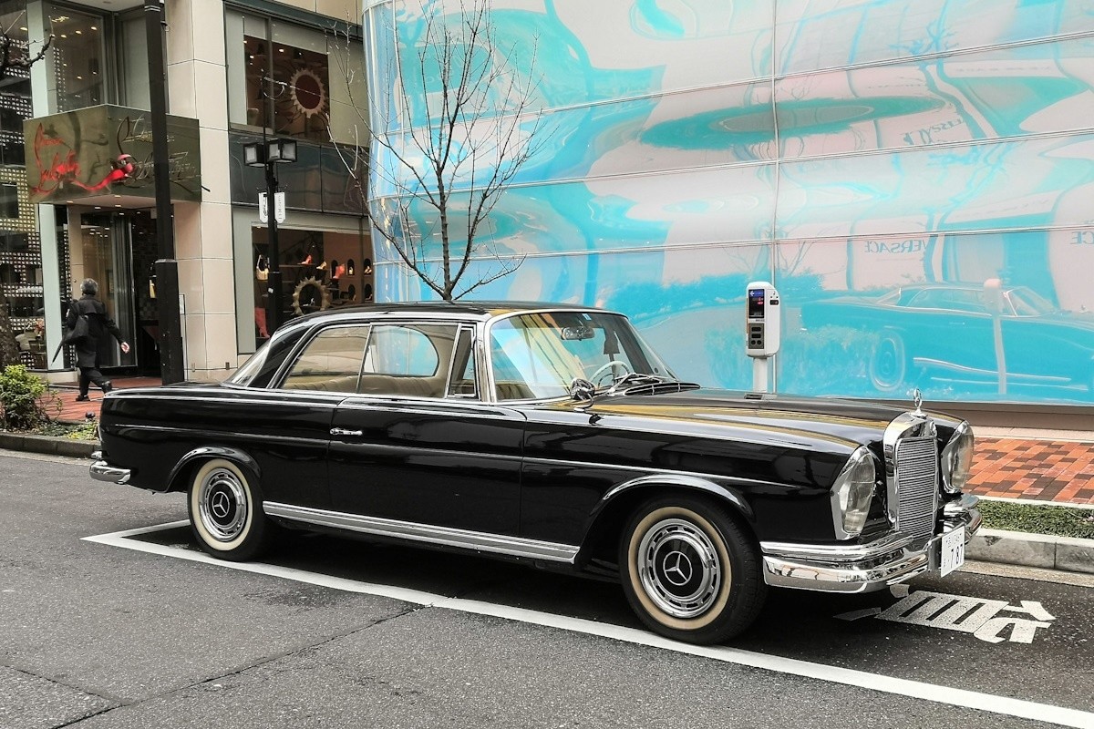 Black Mercedes Benz W111 Coupe front three quarter view, parked on street.