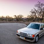 Smoke Silver Mercedes-Benz 190E 2.3-16 Cosworth parked outdoors, showcasing its classic sedan profile.