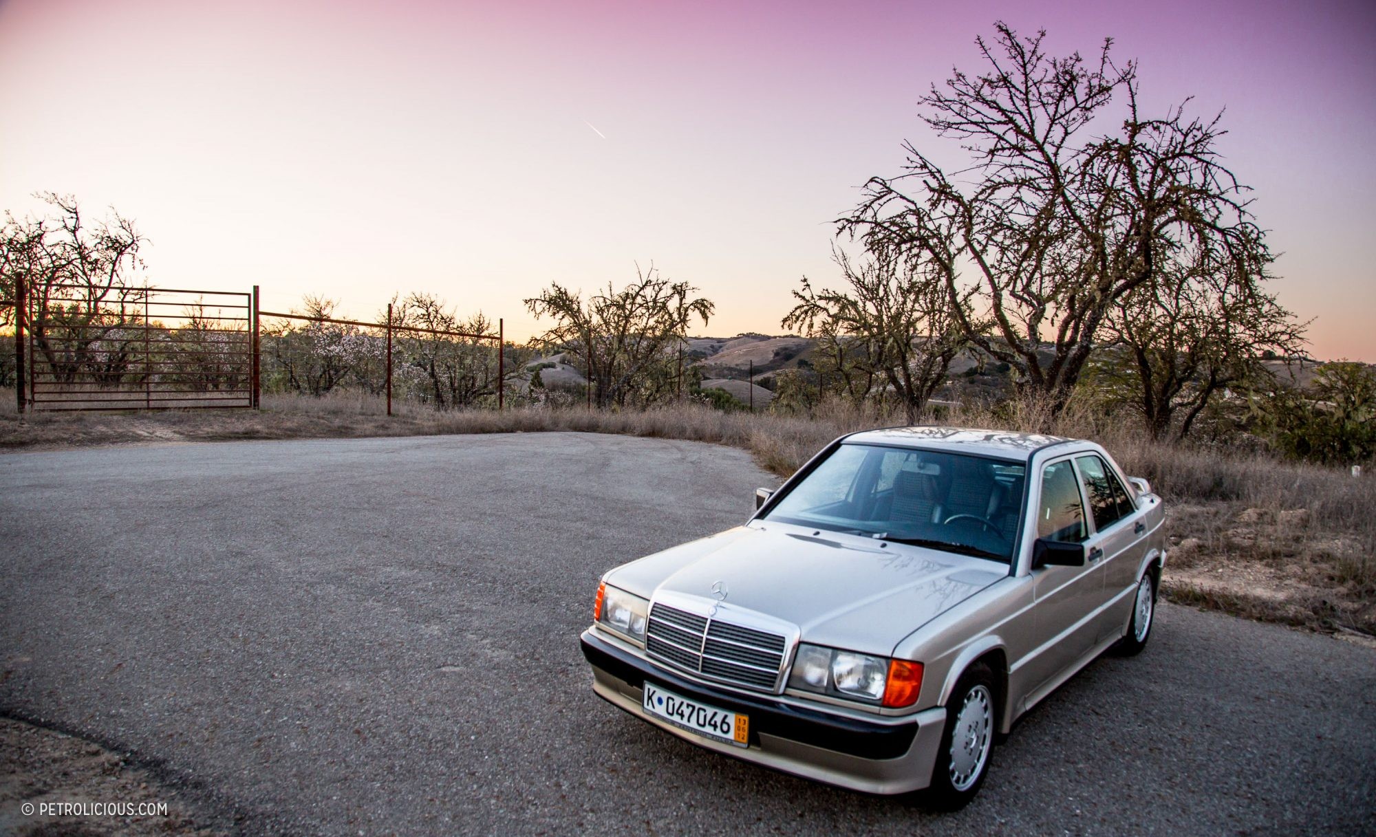 Smoke Silver Mercedes-Benz 190E 2.3-16 Cosworth parked outdoors, showcasing its classic sedan profile.