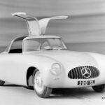 The 1952 Mercedes-Benz 300SL race car, the original gullwing Mercedes, parked on a track, emphasizing its racing heritage and innovative door design.