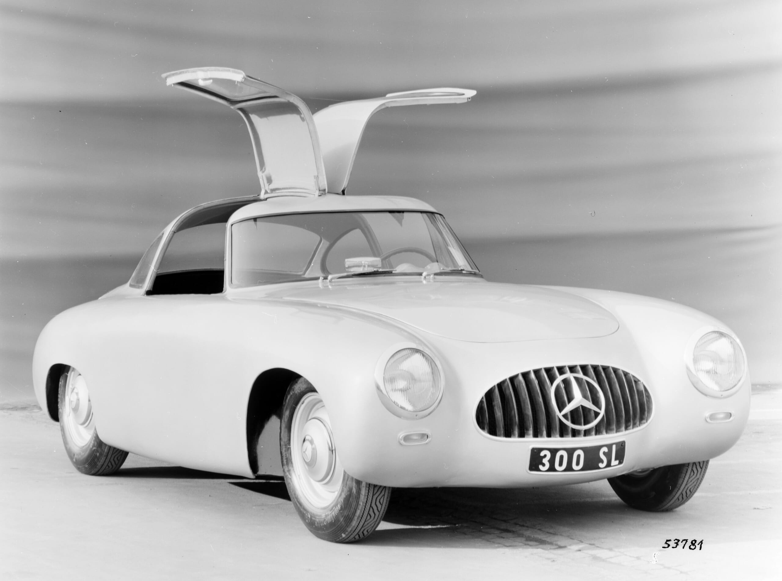 The 1952 Mercedes-Benz 300SL race car, the original gullwing Mercedes, parked on a track, emphasizing its racing heritage and innovative door design.