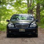 Front three quarter view of a silver 2002 Mercedes-Benz C32 AMG parked outdoors.