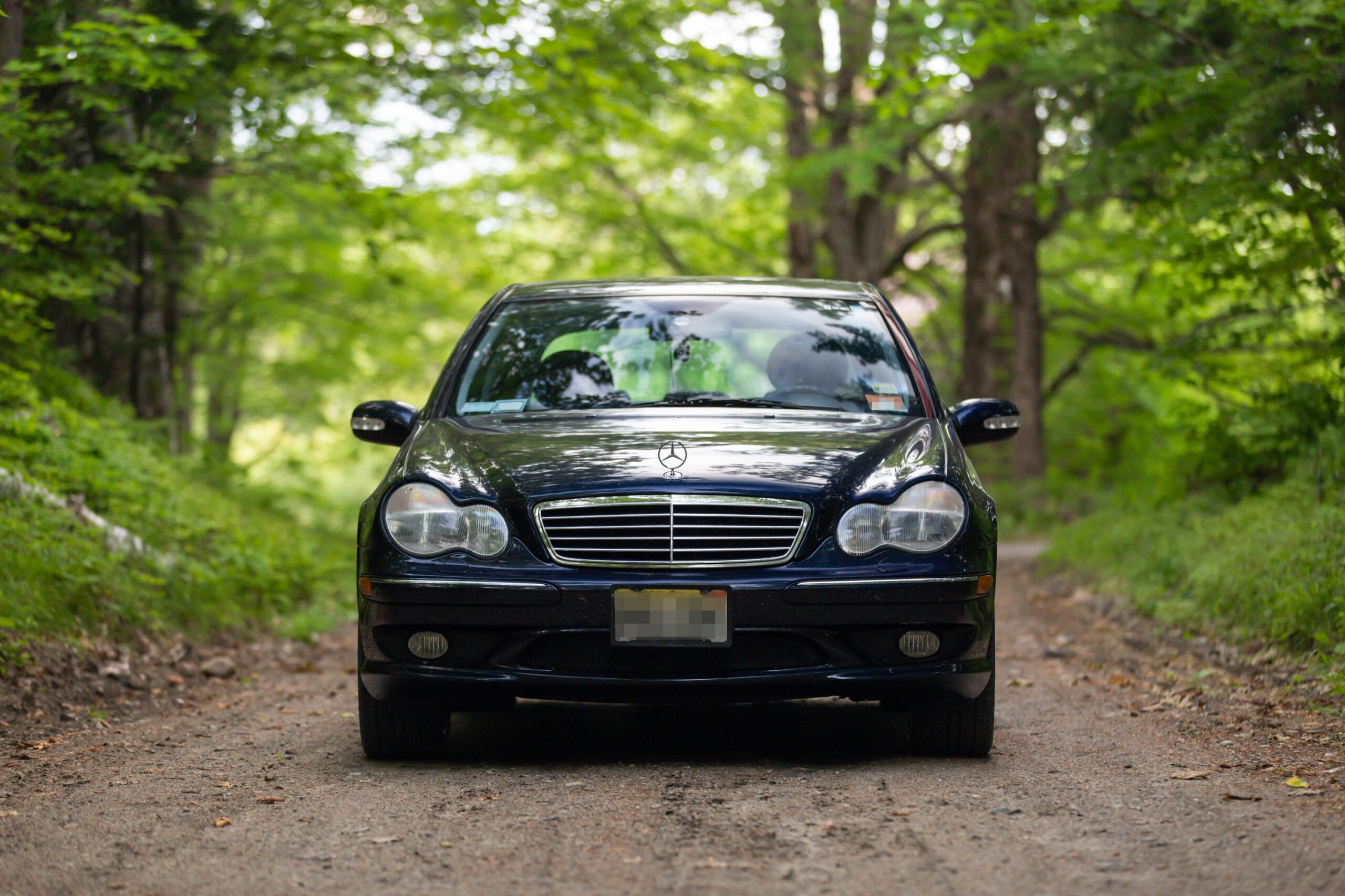 Front three quarter view of a silver 2002 Mercedes-Benz C32 AMG parked outdoors.