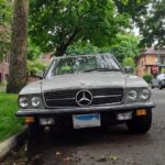 Front quarter view of a slightly worn 1981 Mercedes-Benz 380SL parked on a street, showcasing its classic roadster design