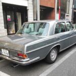 Front quarter view of a silver Mercedes-Benz W109 3.5 parked on a city street in Tokyo, highlighting its elegant lines and classic Mercedes-Benz design.