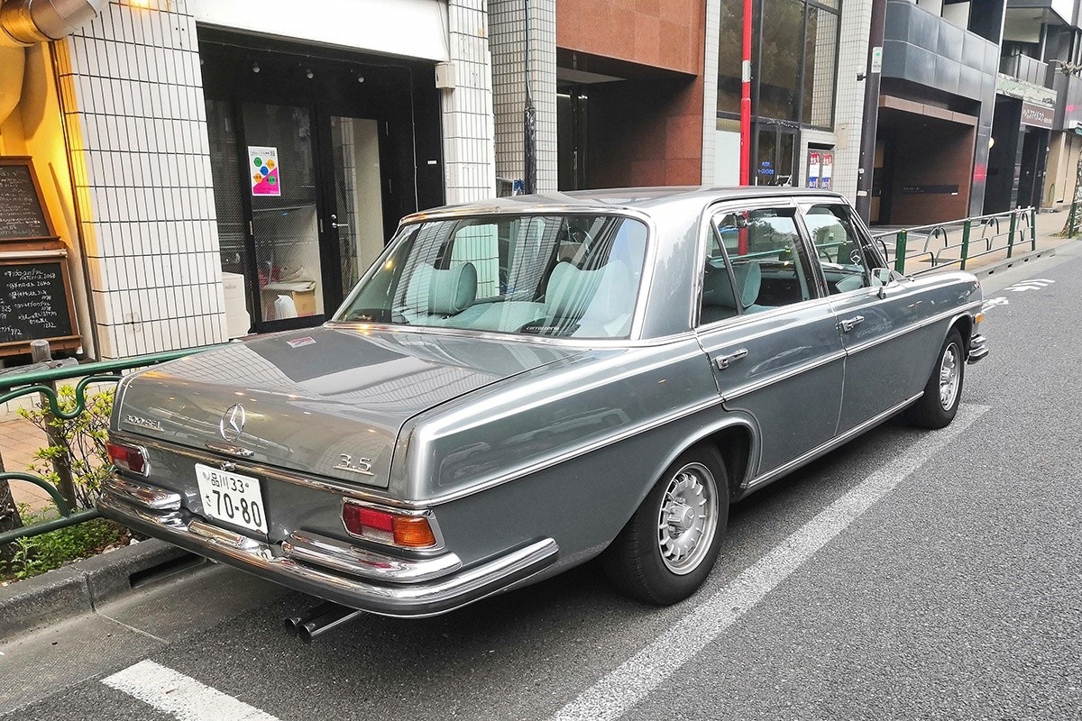 Front quarter view of a silver Mercedes-Benz W109 3.5 parked on a city street in Tokyo, highlighting its elegant lines and classic Mercedes-Benz design.